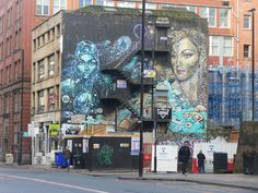 a large building with graffiti on it's side next to a street and sidewalk