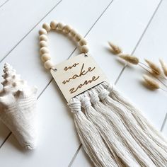 a tasseled necklace with a wooden sign that says make zone next to some sea shells