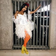 a woman dressed as a jail cell with white feathers and orange tights, posing for the camera