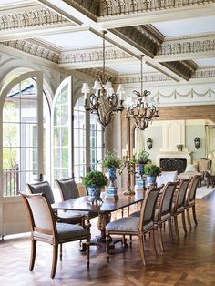 a dining room table with chairs and chandelier in front of large arched windows