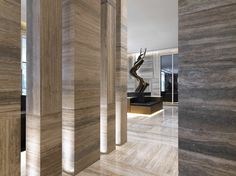 the interior of a modern house with marble walls and flooring, along with an abstract sculpture