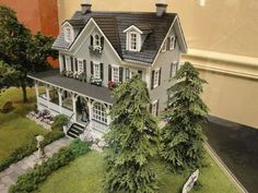 a model house with trees and bushes in front of it