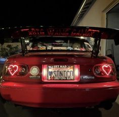 the back end of a red sports car with its lights turned on at night time