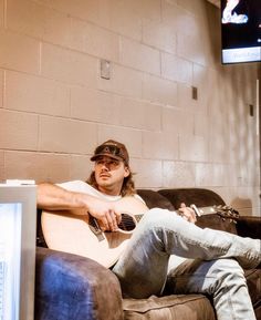 a man sitting on top of a couch holding a guitar