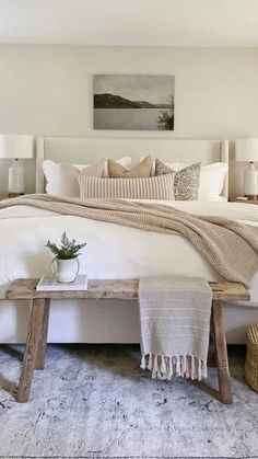 a bed with white linens, pillows and blankets on top of it in a bedroom