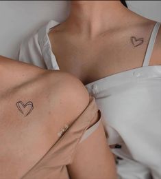 two women with small tattoos on their chests, one is wearing a white shirt