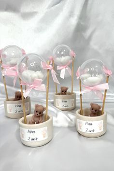 four small teddy bears are in little vases