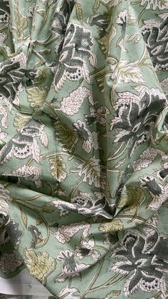 the fabric is green and white with flowers on it, as well as other things