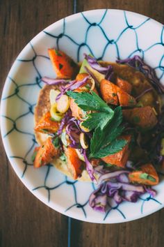 a white plate topped with carrots, cabbage and other food on top of a wooden table