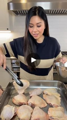 a woman is cooking chicken in the kitchen