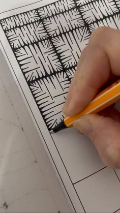 a person holding a pencil in their left hand and drawing on paper with black ink