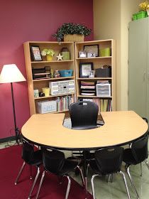 a table with chairs around it in front of a bookcase and bookshelf