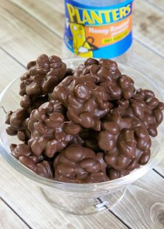 a bowl full of chocolate covered peanuts next to a bottle of planters peanut butter