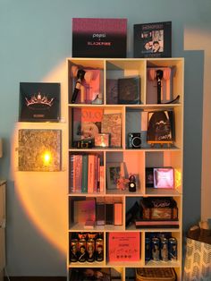 a bookshelf filled with lots of books in front of a blue wall next to a lamp