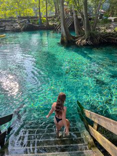 a woman in a bathing suit walking up some steps to the water at plit