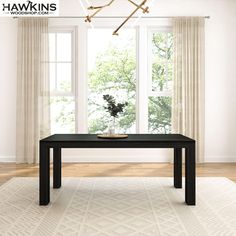 a black table sitting on top of a white rug in front of a large window