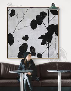 a woman sitting at a table in front of a painting on the wall above her