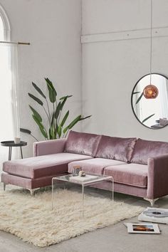 a living room with a couch, table and round mirror on the wall above it