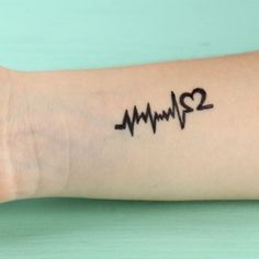 a person with a tattoo on their arm has a heart beat drawn on the wrist