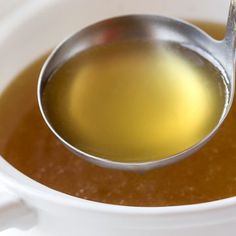 a spoon filled with liquid sitting on top of a white bowl