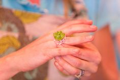 a close up of a person's hand holding a flower ring