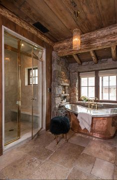 an old fashioned bathtub in a rustic bathroom with stone walls and flooring, along with a large window