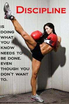 a woman with red boxing gloves on her feet kicking a kickbox in front of a wall