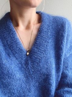 a woman wearing a blue sweater and earrings