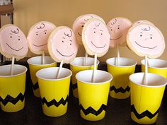 a table topped with yellow cups filled with cupcakes and smiley faces on top of them