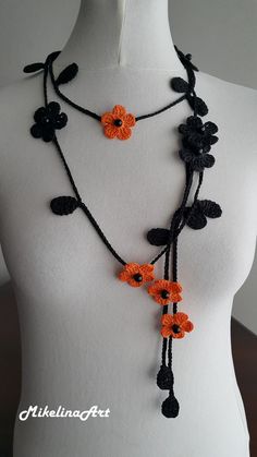 an orange and black crochet flower necklace on a mannequin