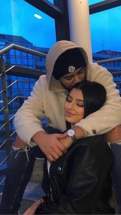 a man and woman hugging each other while sitting on stairs