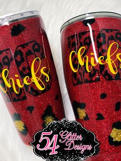 two red glitter tumbles with black and gold designs on them, one has the word chick's written on it