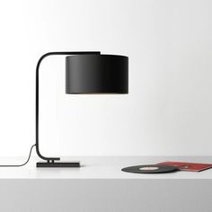 a black lamp sitting on top of a white table next to a record and remote control