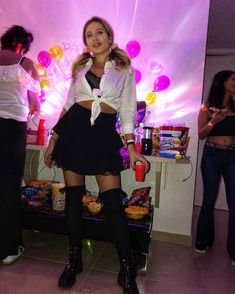 a woman standing in front of a table with food and drinks on top of it