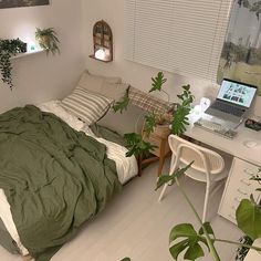 a bedroom with a bed, desk and laptop on the table in front of it