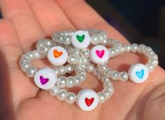 a person is holding several beads in their hand with hearts painted on the bead