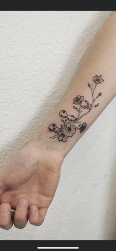 a woman's arm with a small flower tattoo on the left side of her arm