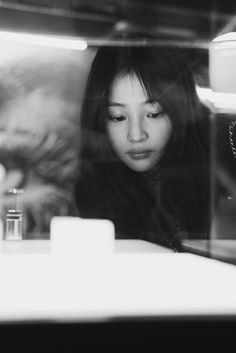 a woman looking at her cell phone in a store window with the reflection of another person