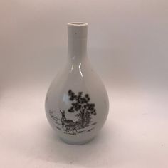 a white vase sitting on top of a table next to a tree and bird design