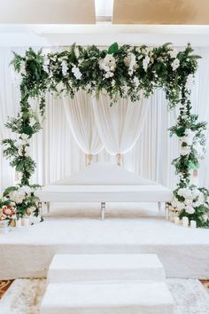 a white wedding ceremony setup with flowers and greenery