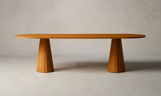 an oval wooden table sitting on top of a white floor next to a gray wall