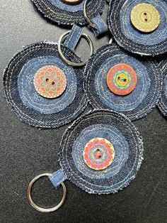 six denim circles with buttons on them sitting on top of a black table next to a pair of scissors