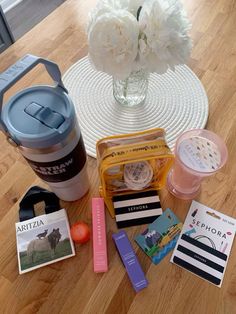 the contents of a travel bag laid out on a wooden table next to a coffee cup