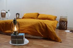 a bed sitting on top of a hard wood floor next to a table with a lamp