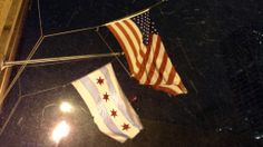 two american flags are hanging on the side of a building in new york city at night