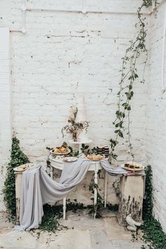 the table is set up with desserts on it and greenery in front of it