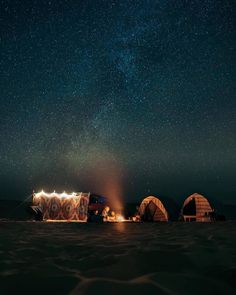 the night sky is filled with stars above some yurts and tents in the desert