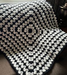 a black and white crocheted blanket sitting on top of a couch