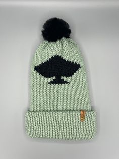 a knitted beanie with an image of a black bird on the front and green background