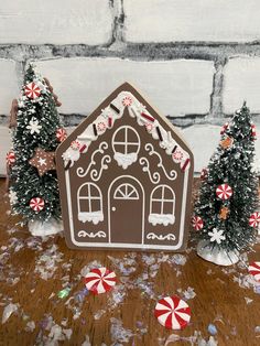 a gingerbread house with trees and candy canes on the floor next to it